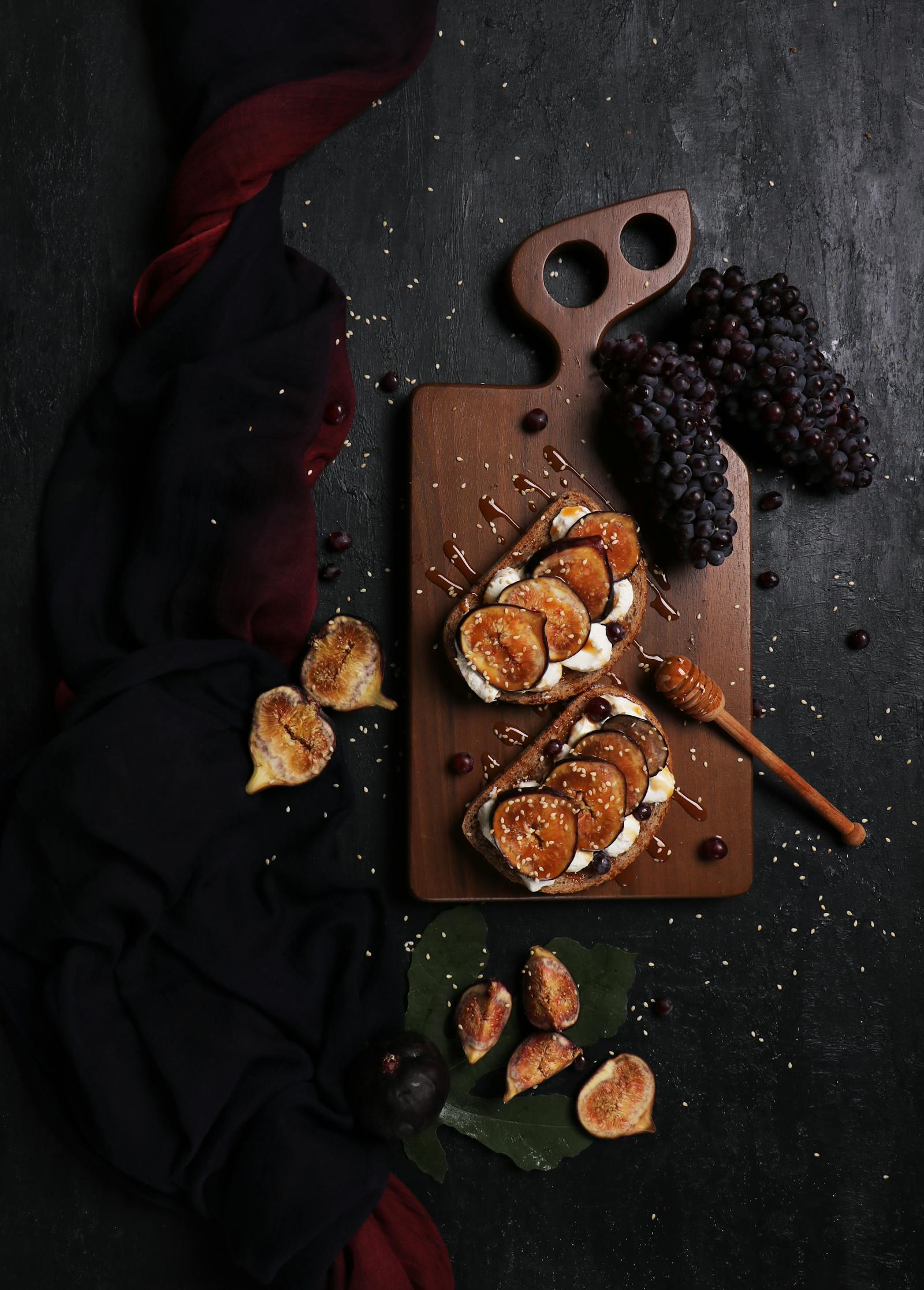 A long table set with bread, olive oil, and a glass carafe, shot in raking side-light, deep editorial mood.